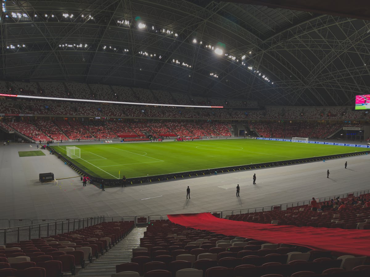 Spacious indoor soccer stadium filled with spectators. Bright lighting enhances the green field.